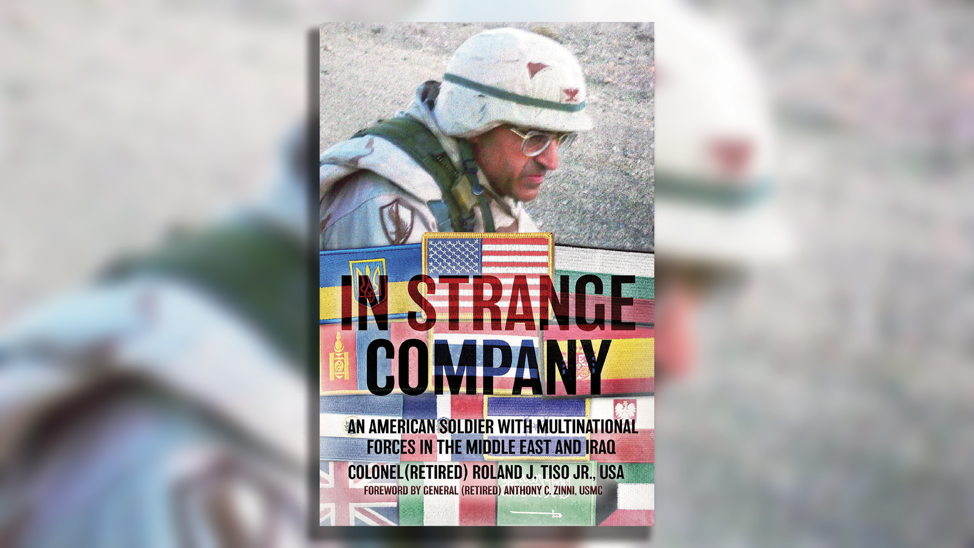 Book cover of 'In Strange Company: An American Soldier with Multinational Forces in the Middle East and Iraq' by Colonel (Retired) Roland J. Tiso Jr., USA, with foreword by General (Retired) Anthony C. Zinni, USMC. The cover features a photograph of a soldier in desert camouflage uniform and white cap in an arid landscape. The background is overlaid with a collage of various international flag patches including the American flag, Ukrainian flag, and other national emblems representing multinational military cooperation. The title 'IN STRANGE COMPANY' appears in large black letters across the center.