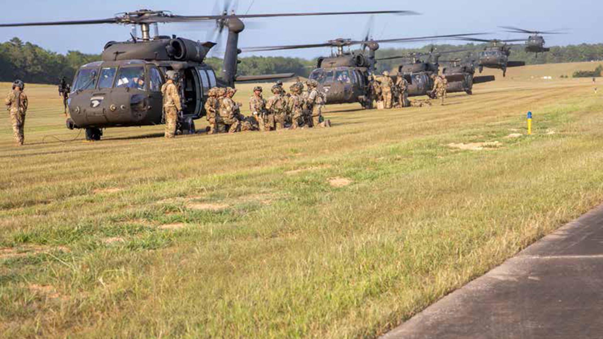 Picture shows helicopters landing in a single file line and dropping off soldiers during a major training event