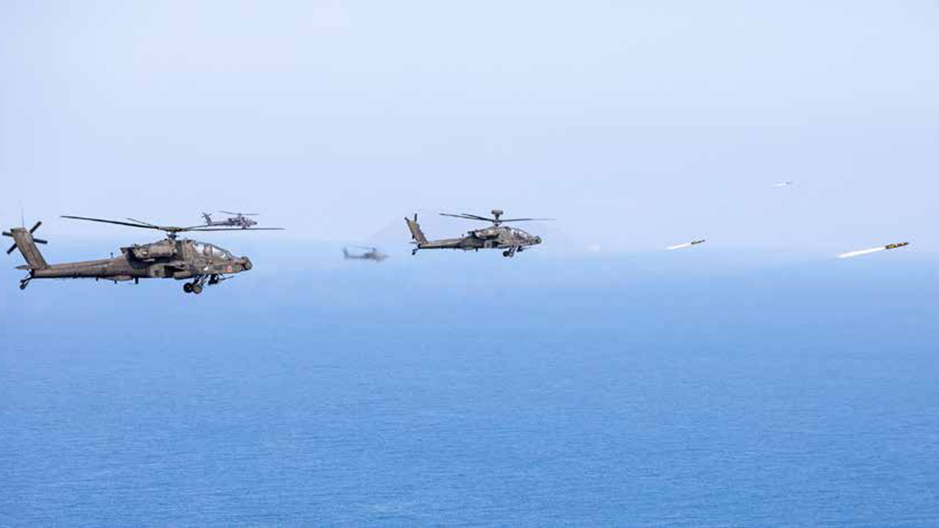 picture of multiple apache helicopters firing hellfire missiles at a range complex in Greece.