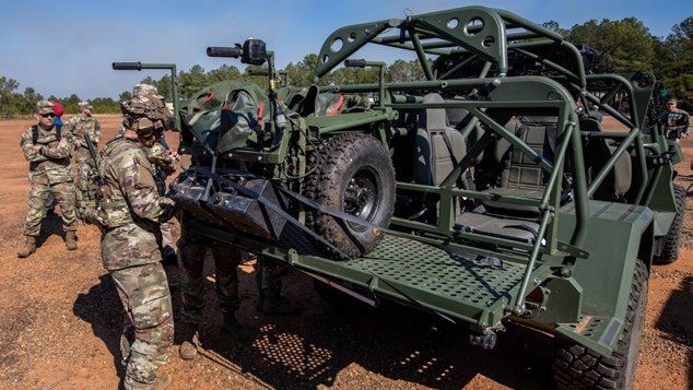 Military vehicle with communication equipment parked at night under a starry sky, with a red light trail across the scene.